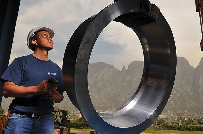 A man standing in front of a large metal ring.