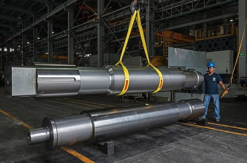 A man standing next to a large metal pipe in a factory.