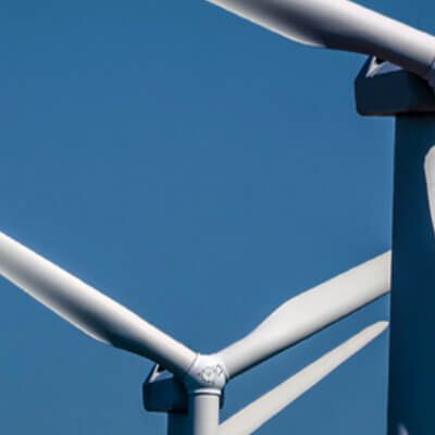 A group of wind turbines against a blue sky.