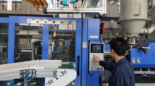 A man is pointing at a machine in a factory.