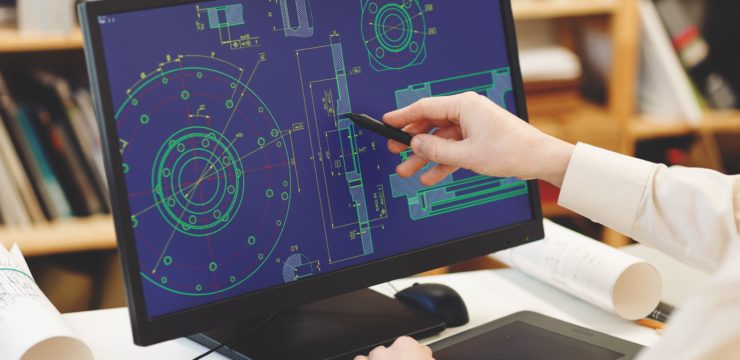 A person is working on a computer with blueprints on it.