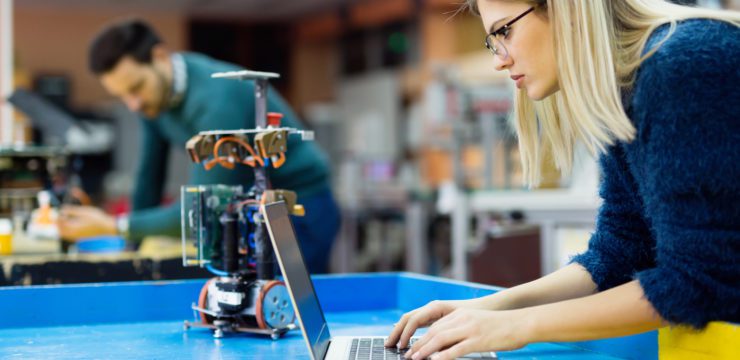 A woman working on a laptop in a factory.