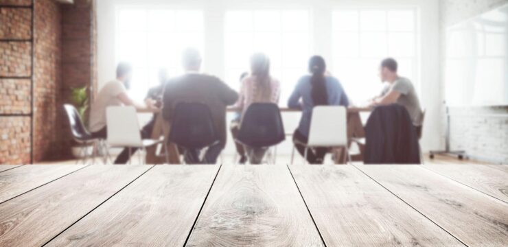 A group of people sitting around a wooden table in a conference room.