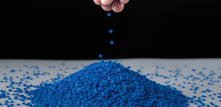 A person is pouring blue plastic into a pile.