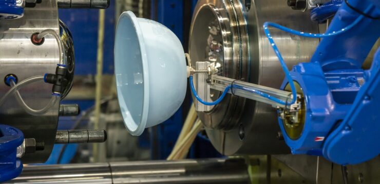 A machine is making a blue plate in a factory.