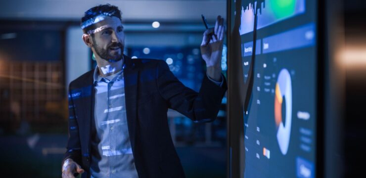 A man is standing in front of a projection screen.