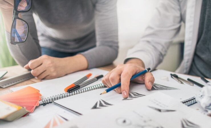 Two people working on a design project at a desk.