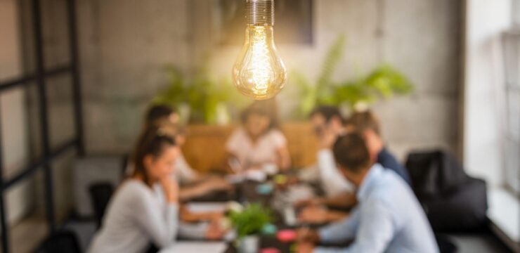 A group of people sitting around a table with a light bulb hanging above them.